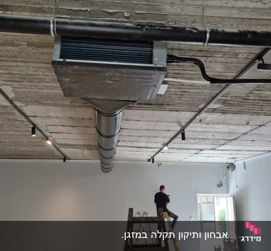 מערכת מיזוג אוויר מותקנת בתקרה עם אדם על סולם